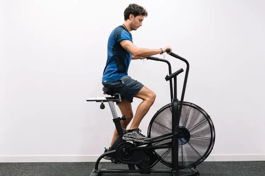Profile of a young man working out on an static bike at a gym